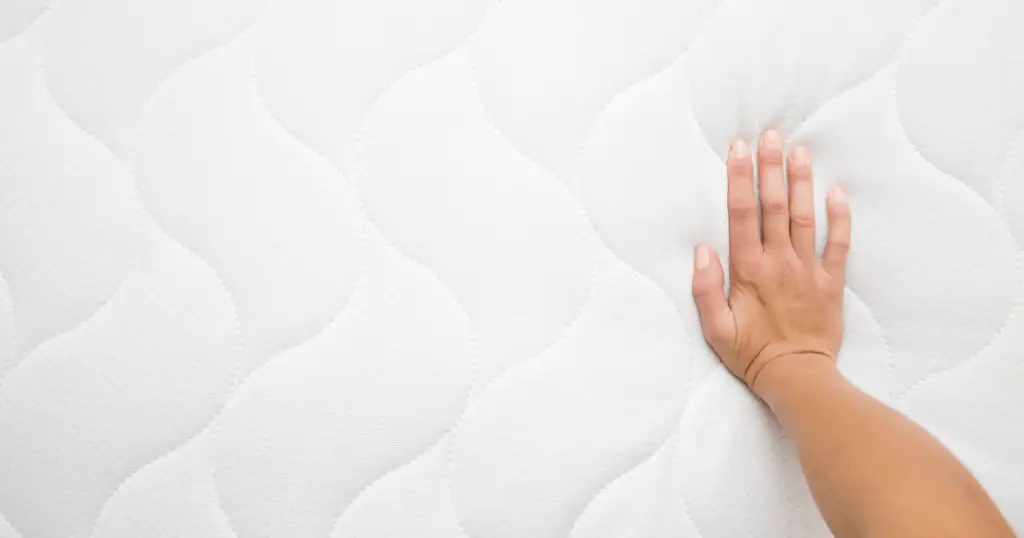 an image of a hand feeling the best mattress topper